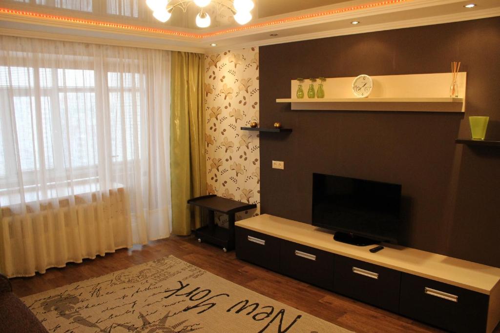 een woonkamer met een flatscreen-tv aan de muur bij Svetlana's Apartments in Sumy