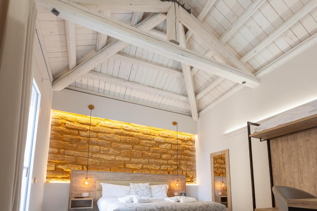 a bedroom with a stone wall above a bed at Oneira Rooms in Agrigento
