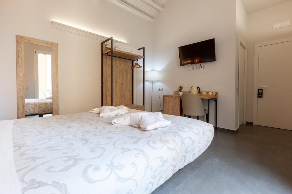 a bedroom with a white bed and a desk at Oneira Rooms in Agrigento