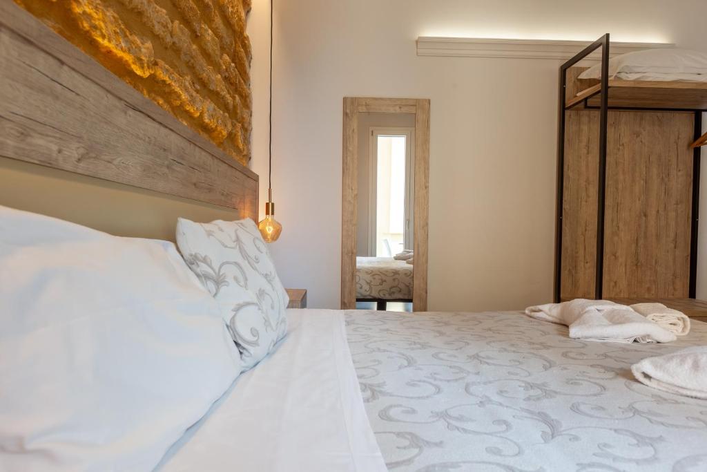 a bedroom with a large bed with white sheets at Oneira Rooms in Agrigento