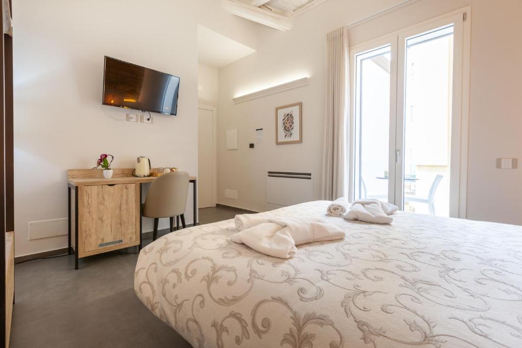 a bedroom with a bed and a desk and a television at Oneira Rooms in Agrigento