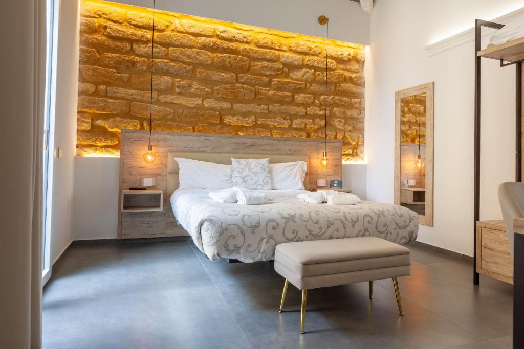 a bedroom with a large bed and a stone wall at Oneira Rooms in Agrigento