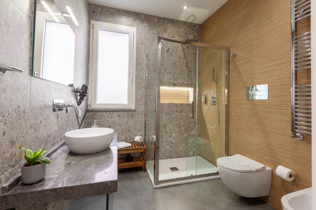 a bathroom with a toilet and a sink and a shower at Oneira Rooms in Agrigento