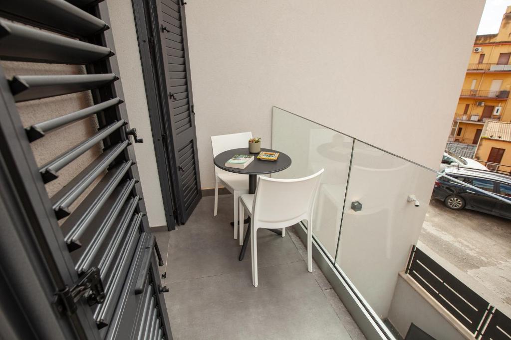 a small balcony with a table and white chairs at Oneira Rooms in Agrigento