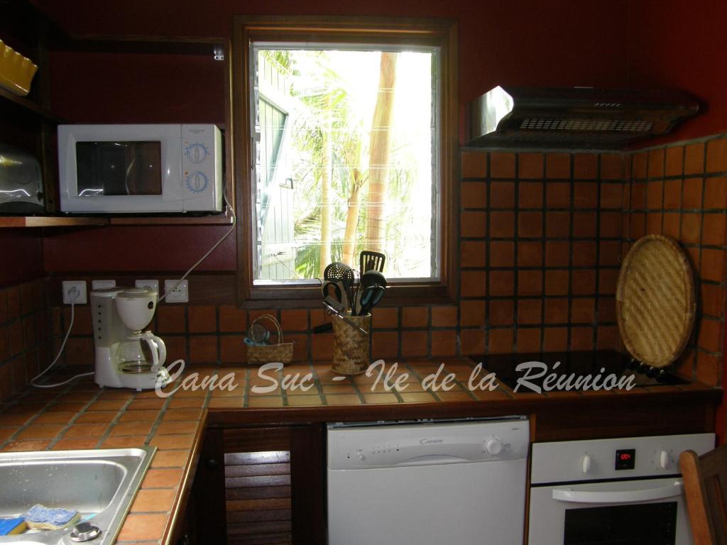 a kitchen with a counter with a sink and a window at Cana Suc in Sainte-Rose