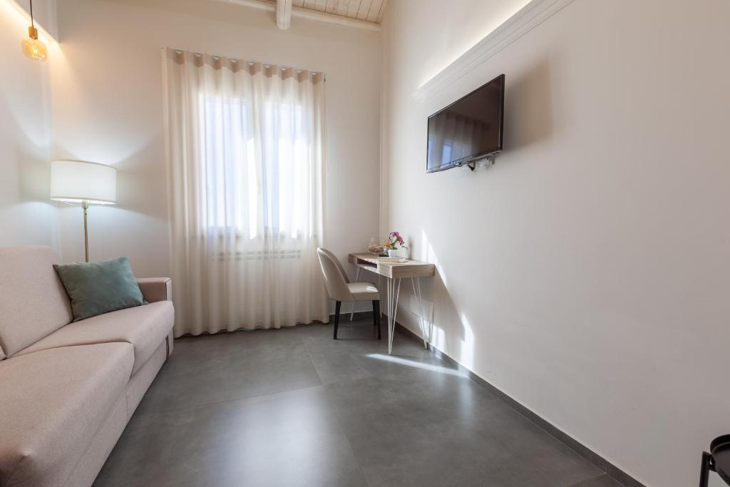 a white living room with a couch and a table at Oneira Rooms in Agrigento