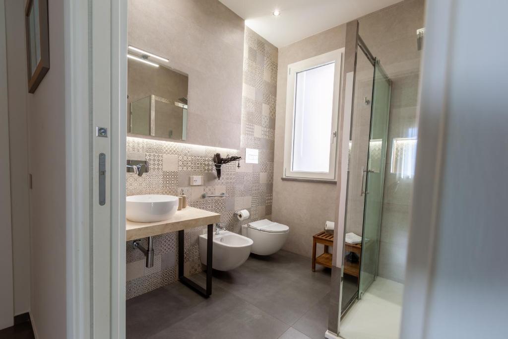 a bathroom with two sinks and a toilet and a shower at Oneira Rooms in Agrigento
