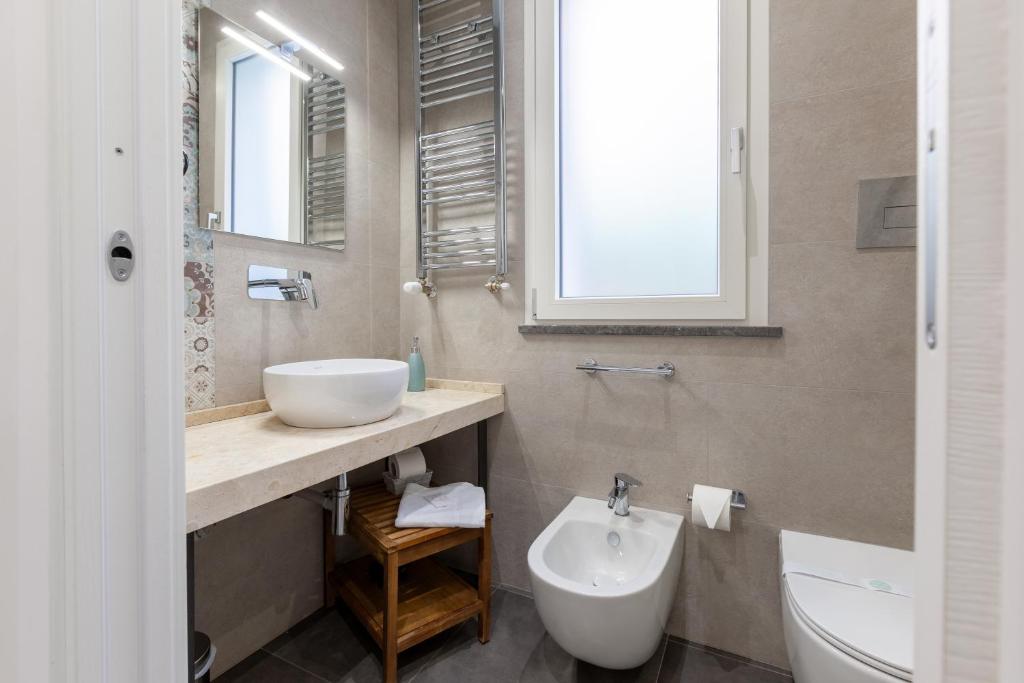 a bathroom with a sink and a toilet and a mirror at Oneira Rooms in Agrigento