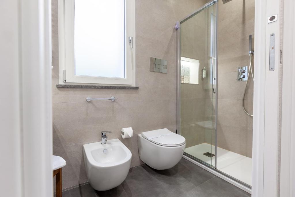 a bathroom with a toilet and a glass shower at Oneira Rooms in Agrigento