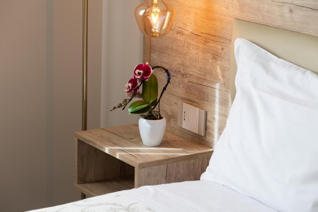 a vase with a flower on a night stand next to a bed at Oneira Rooms in Agrigento