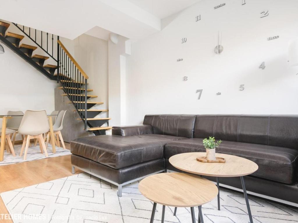 a living room with a black leather couch and a table at Casa Arcangel in Castiello de Jaca
