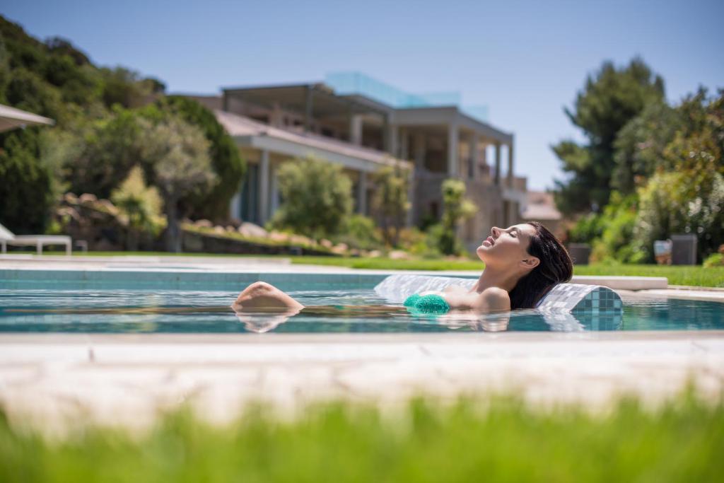 a woman laying in a swimming pool at Chia Laguna - Hotel Village in Chia