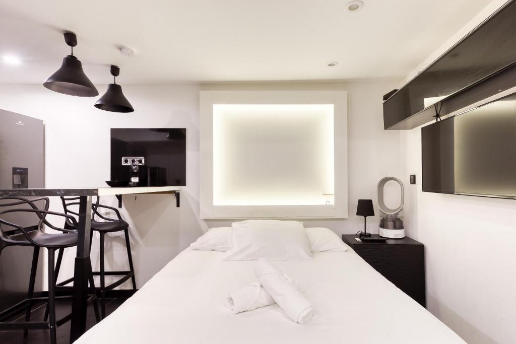 - un lit blanc dans une chambre avec une table et des chaises dans l'établissement Saint Michel, à Paris