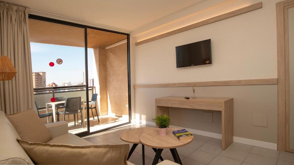 a living room with a couch and a tv on a wall at Dynastic Rooms Apartments in Benidorm