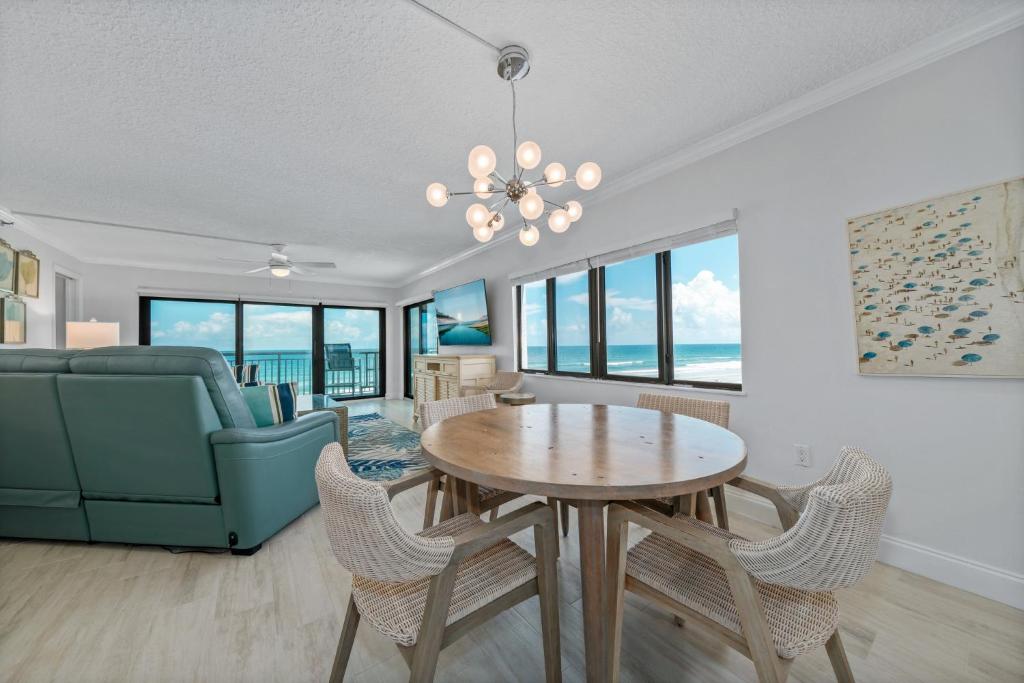a living room with a table and a couch at Corner oceanfront views with wrap around balcony located on the no-drive beach! in New Smyrna Beach