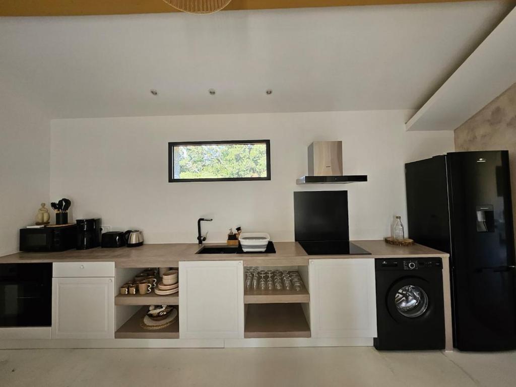 La cuisine est équipée d'un réfrigérateur noir et d'un lave-vaisselle. dans l'établissement Casa Baracheddu avec vue panoramique, à Cuttoli-Corticchiato