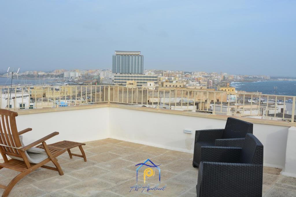 a balcony with two chairs and a view of a city at Scaglione Palace in Gallipoli