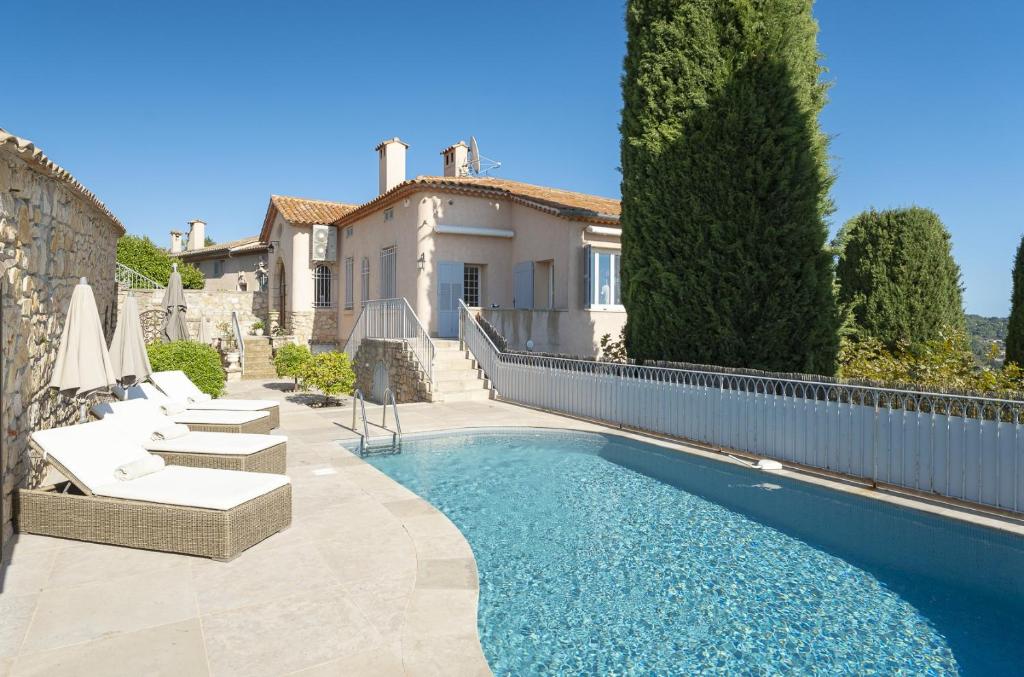 une piscine avec des chaises et une maison dans l'établissement Villa La Pax, à Mougins
