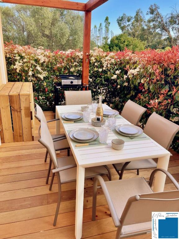 - une table et des chaises blanches sur une terrasse fleurie dans l'établissement Heated Pools, à Porto-Vecchio