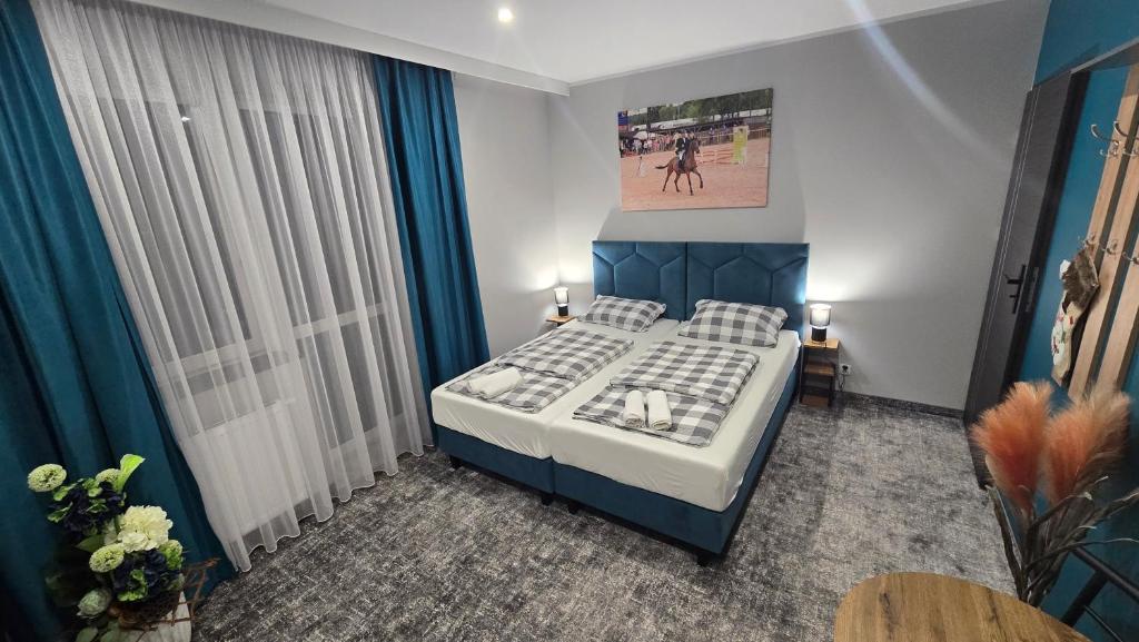 a bedroom with a bed in a room with blue curtains at Pensjonat Lubianka in Starachowice