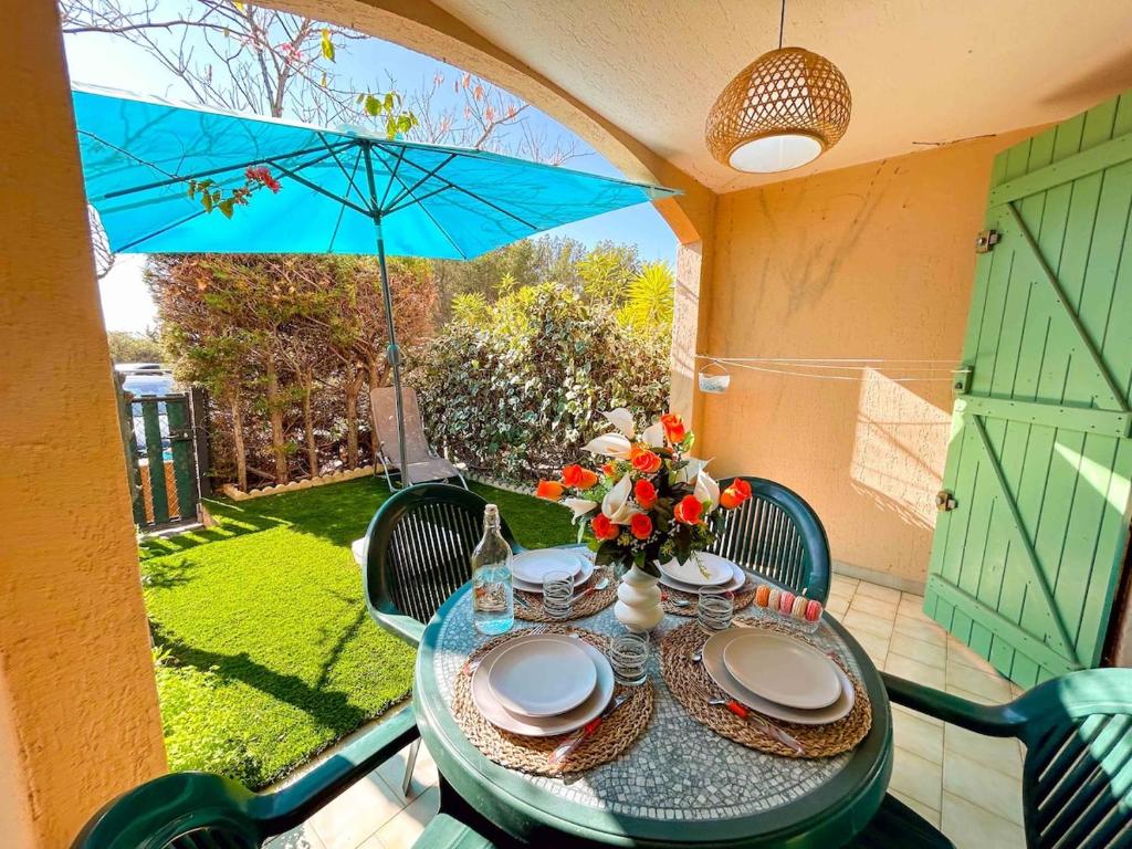 - une table avec des assiettes et un parasol bleu sur la terrasse dans l'établissement Studio en rez-de-jardin à Bandol - parking, à Bandol