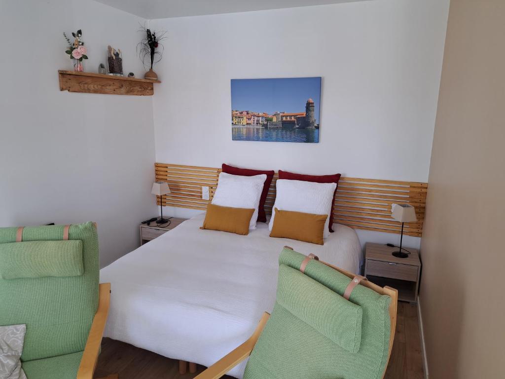 a bedroom with a bed and two chairs at Studio côté jardin in Maureillas
