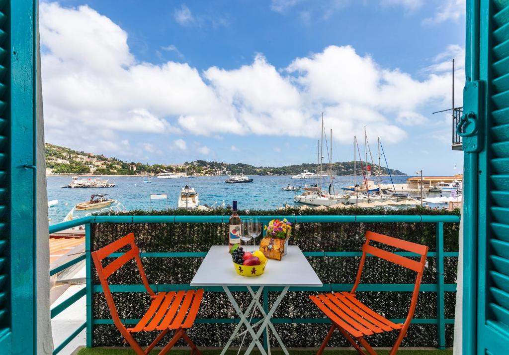 une table et des chaises sur un balcon avec vue sur l'eau dans l'établissement TERRACOTTA AP4457 By Riviera Holiday Homes, à Villefranche-sur-Mer