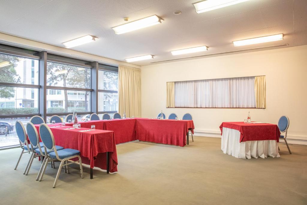 A large meeting room is laid out with tables, red linens, and rows of chairs.