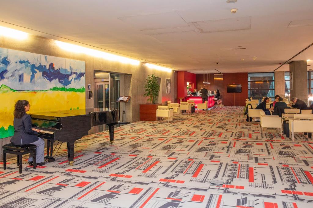 A spacious lobby with a grand piano, reception area and lounge seating.