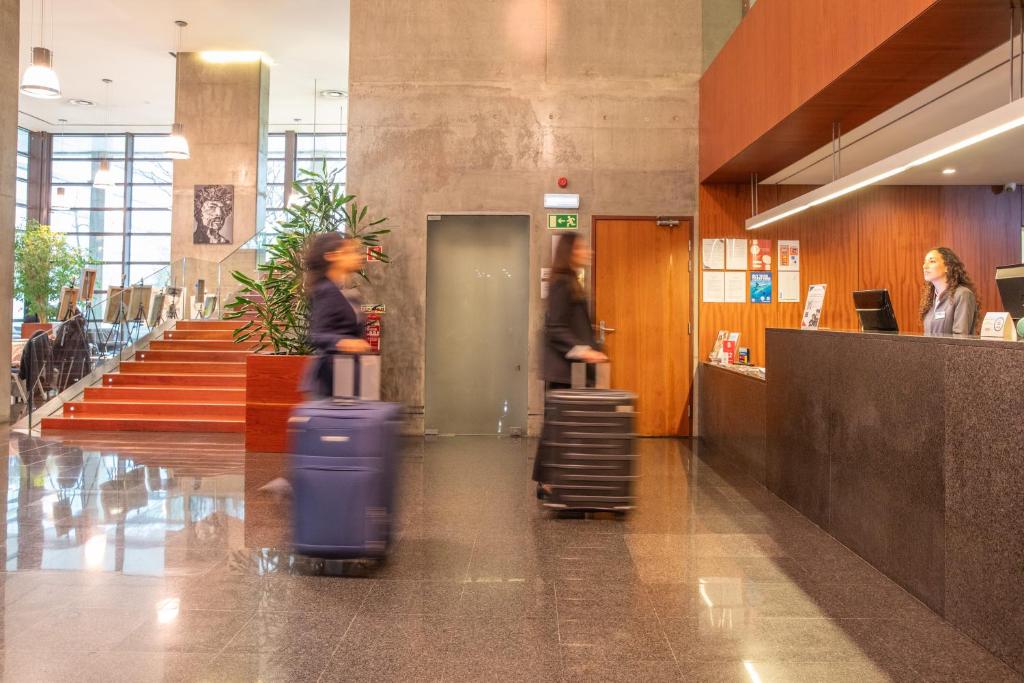 Guests with rolling luggage pass through the bright lobby beside the reception desk.