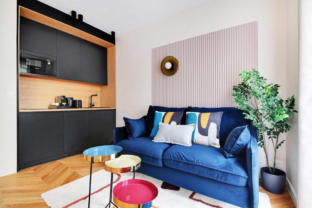 a living room with a blue couch and a kitchen at Lovely Parisian Apartment Near the Eiffel Tower in Paris
