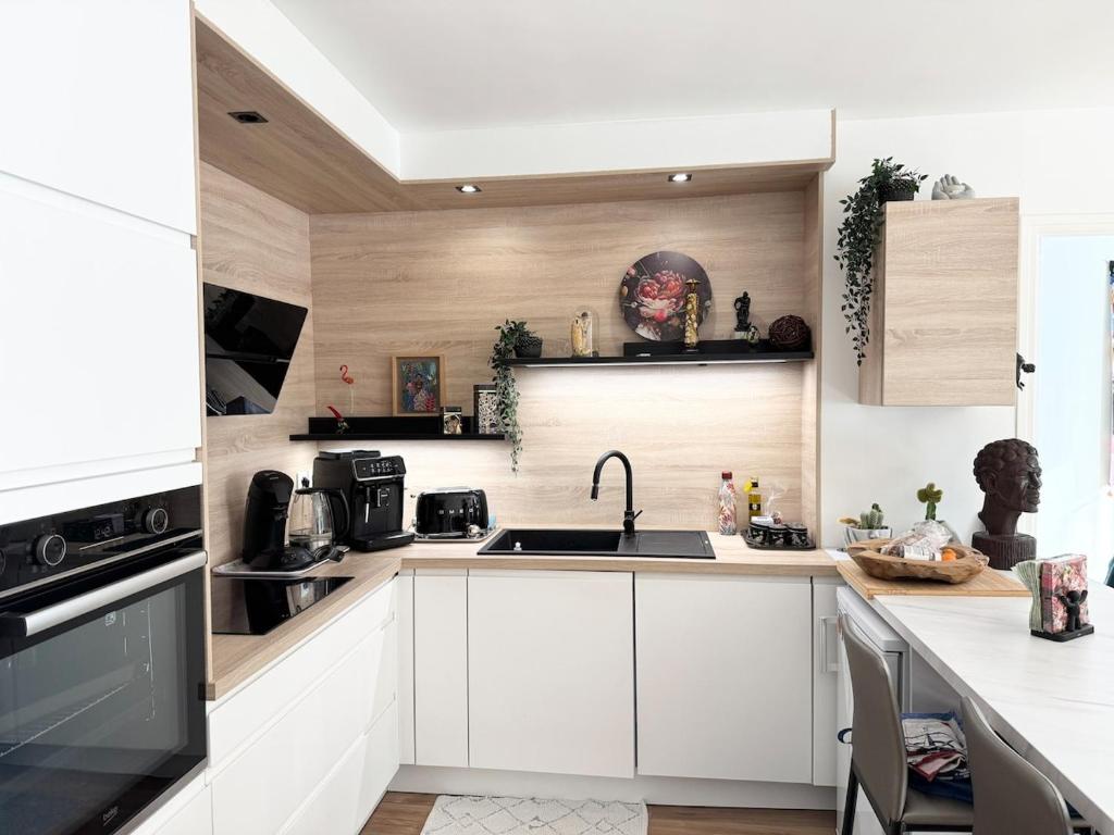 une cuisine avec des armoires blanches et un évier dans l'établissement Appartement de charme, Bénodet, à Bénodet