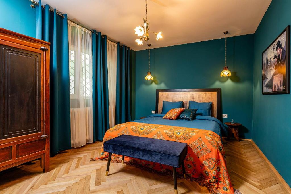 a bedroom with blue walls and a bed with an orange blanket at Eclectic Condo Romexpo 2BR near Metro in Bucharest