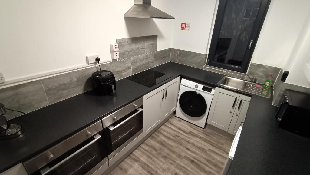 a kitchen with a sink and a washing machine at Comforatable Modern Studios in Nottingham