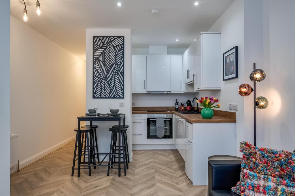 a kitchen with white cabinets and bar stools at Stylish 2 Bedroom Apartment in Belfast in Belfast