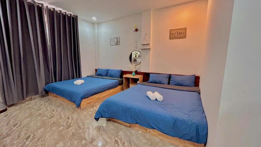 two beds in a room with blue sheets at Ami House Da Lat in Da Lat