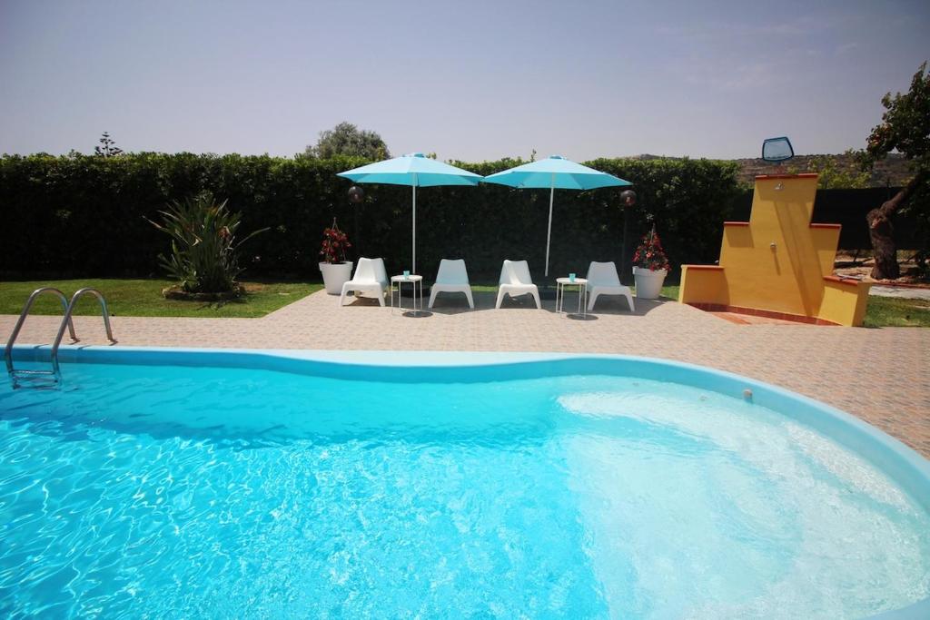 a large blue swimming pool with chairs and umbrellas at HOMESICILY - Total relaxing in a private property in Floridia