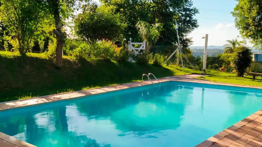 a swimming pool with blue water in a yard at Chalé Confortável e Completo com piscina in Caeté