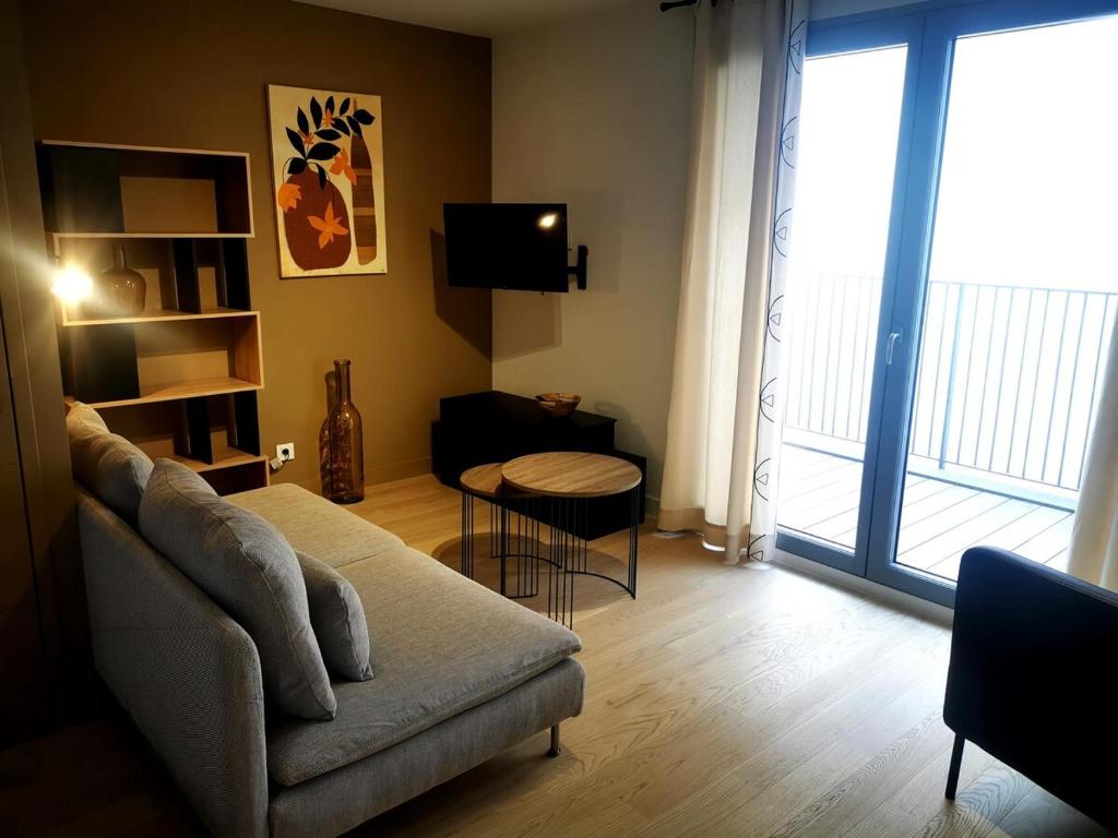 un salon avec un canapé et une grande fenêtre dans l'établissement Toulouse, Bourse nice and comfortable family apartment, à Toulouse