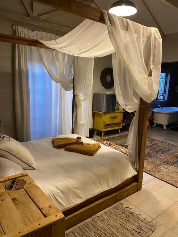 a bedroom with a canopy bed and a television at Studio 101 in Oudtshoorn