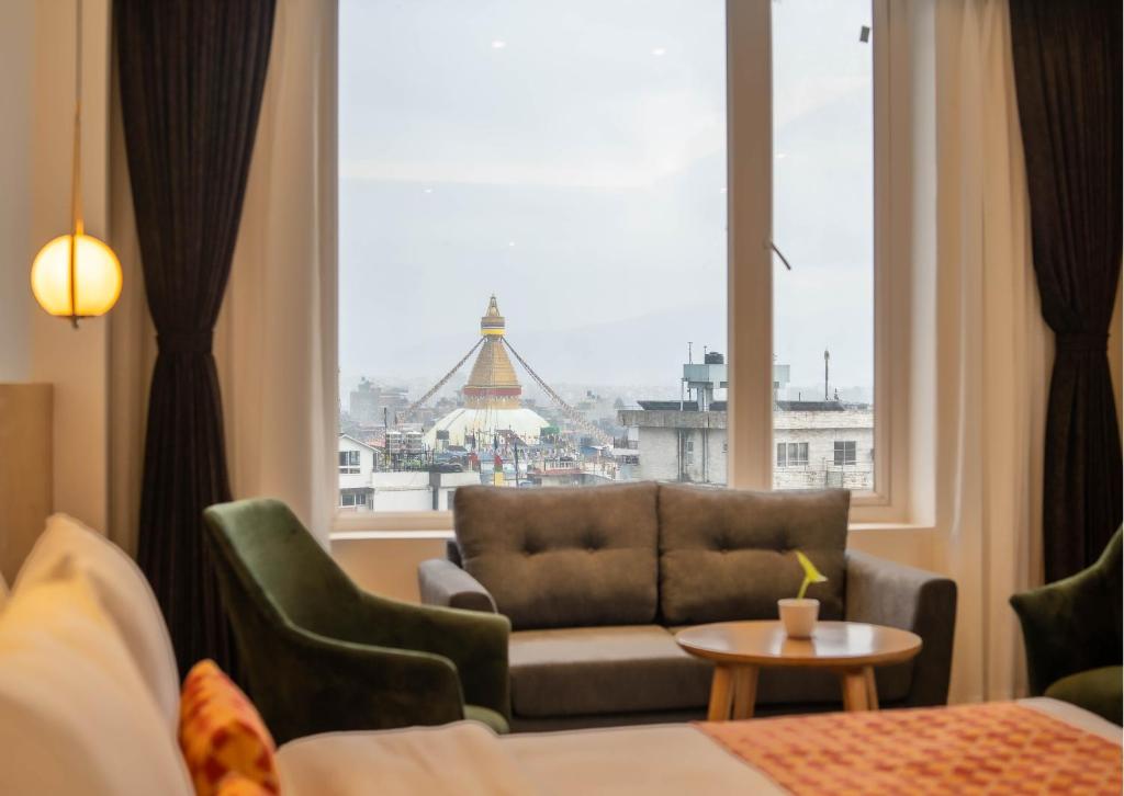 ein Hotelzimmer mit einer Couch und einem großen Fenster in der Unterkunft Hotel Anuttara, Boudha in Baudhatinchule