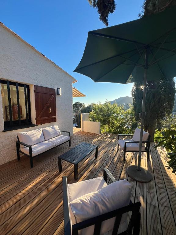 une terrasse en bois avec des chaises et un parasol dans l'établissement Maison Bord de mer Theoule, à Théoule-sur-Mer