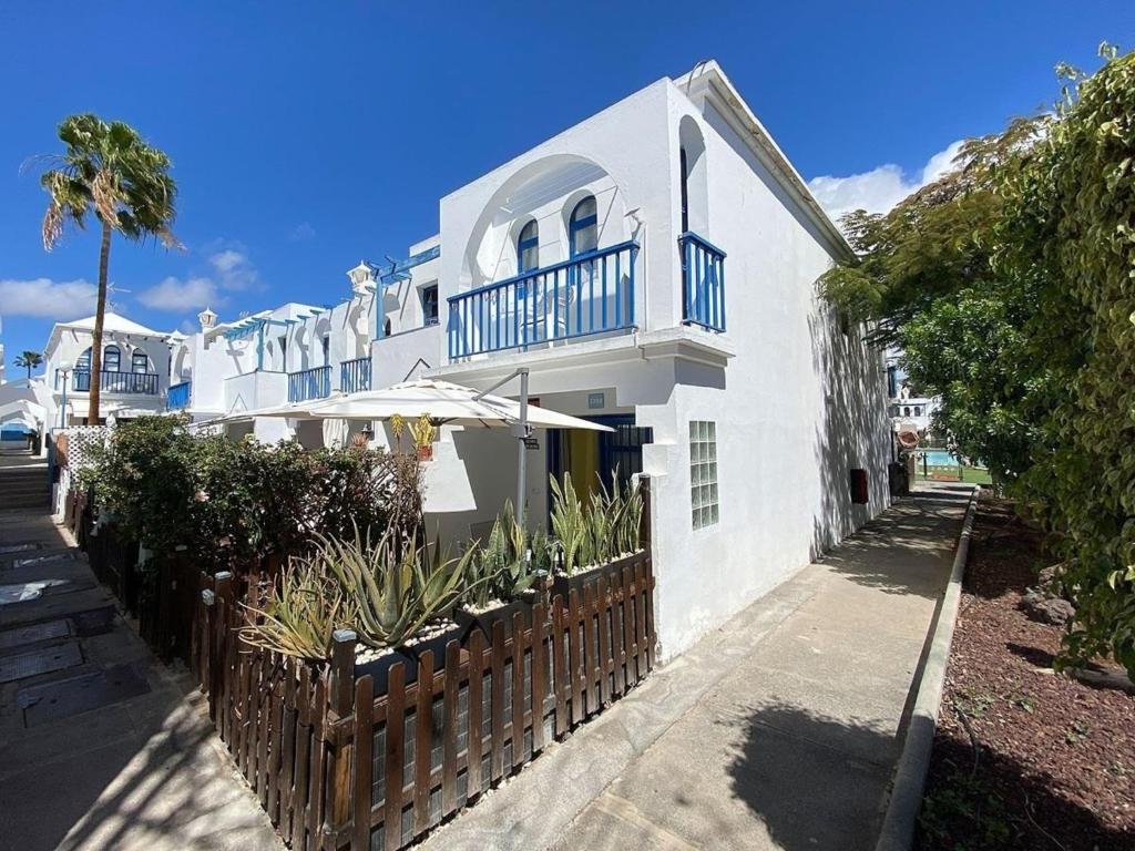 a white house with a fence and an umbrella at PLAYMAR Refugio Palmeras in Maspalomas
