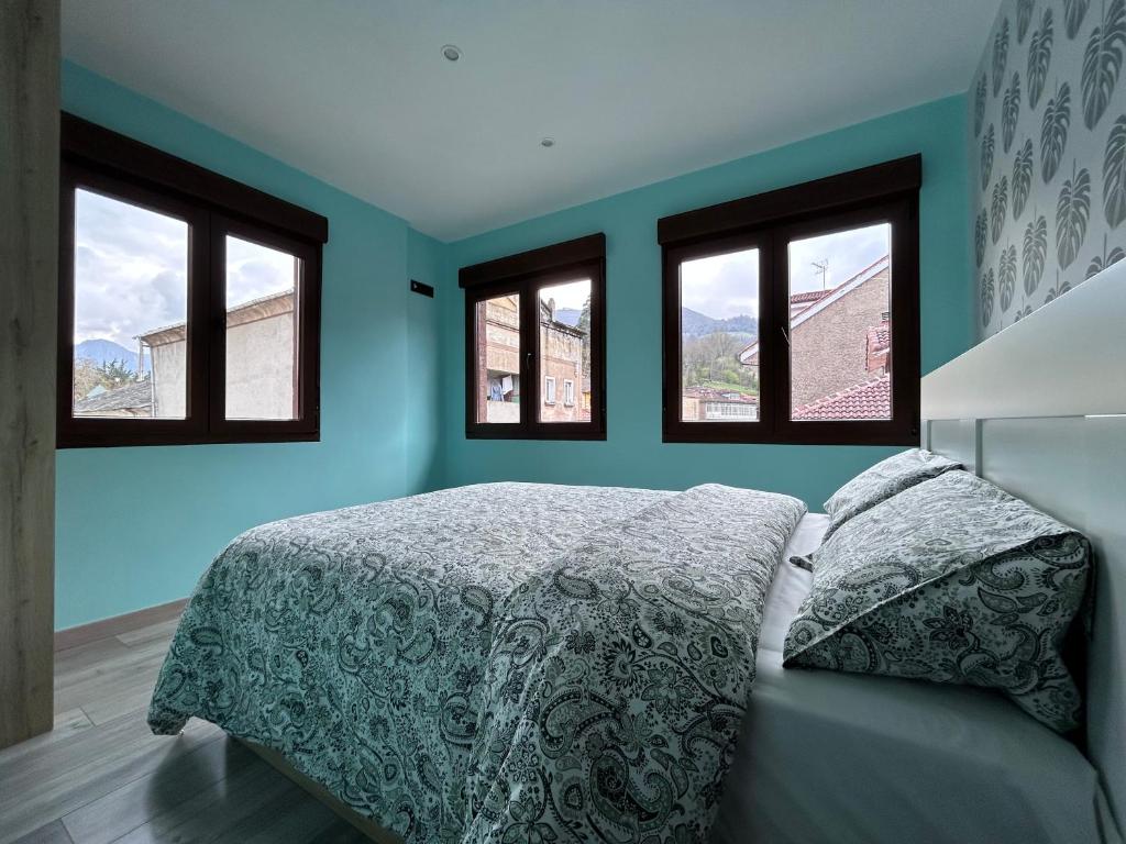 a bedroom with blue walls and a bed with windows at Vistas Sobia San Martín de teverga in San Martín