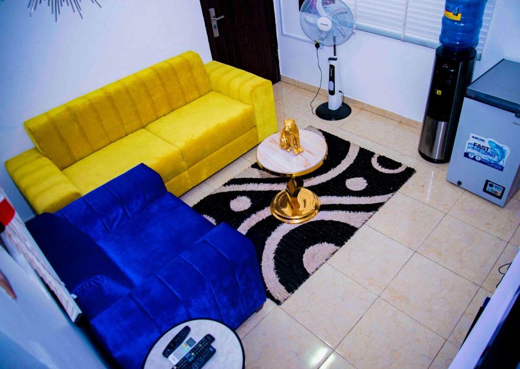 a living room with a yellow couch and a rug at A cozy 1 bed apartment for rent in Suncity Estate in Galadima