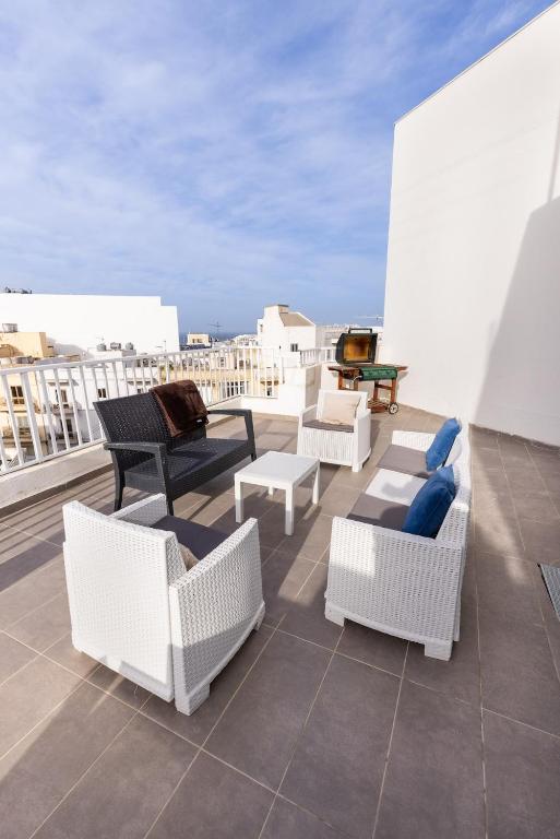 a group of chairs and tables on a roof at Luigi penthouse in St. Paul's Bay