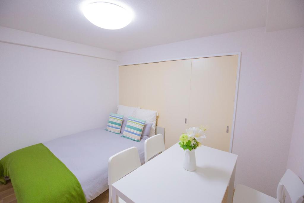 a white bedroom with a bed and a table at 新宿駅 西武新宿駅近 歌舞伎町の快適ゲストハウス LoE3 in Tokyo