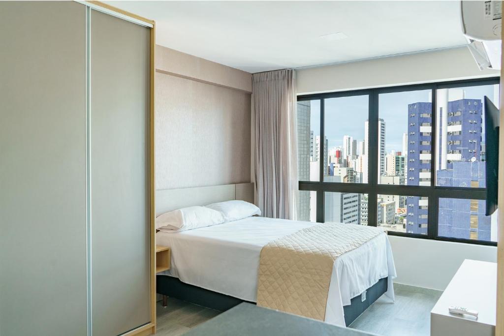ein Hotelzimmer mit einem Bett und einem großen Fenster in der Unterkunft Studio em Boa Viagem Excelente localização in Recife