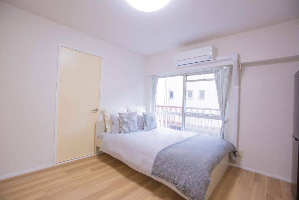 a white bedroom with a bed and a window at 新宿駅 西武新宿駅近 歌舞伎町の快適ゲストハウス LoE3 in Tokyo