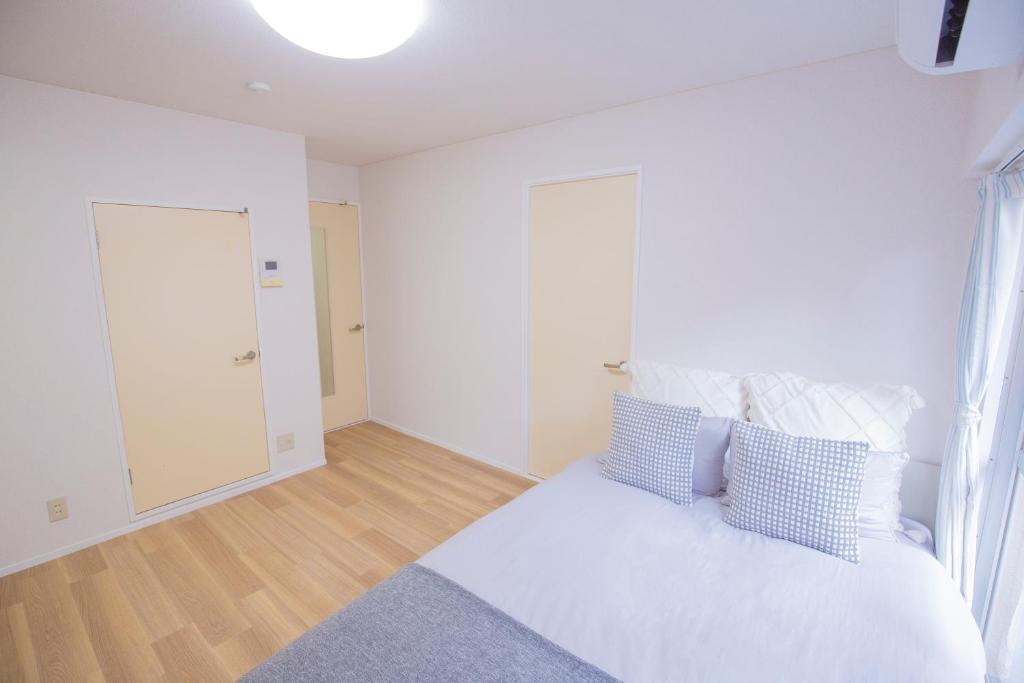 a bedroom with a bed with blue and white pillows at 新宿駅 西武新宿駅近 歌舞伎町の快適ゲストハウス LoE3 in Tokyo